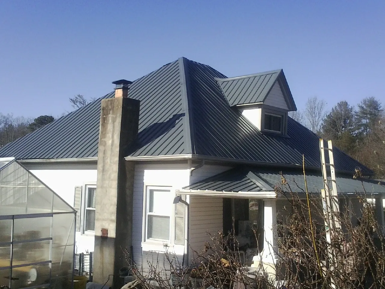 Dark blue standing seam metal roof on a white farmhouse with dormer — Slate & Tile Roof Repair by Roofing Brothers in Hood