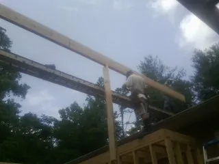 Carpenter setting a ridge beam over a new addition frame — Ice Dam Removal by Roofing Brothers in Hood