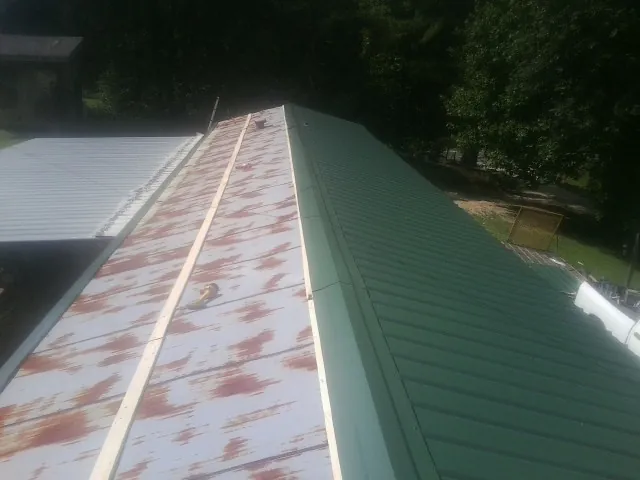 Old rusted panels beside newly installed green metal roofing — Wind Damage Roof Repair by Roofing Brothers in Hood
