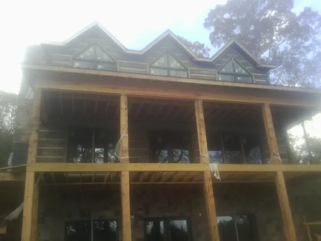 Dormers and porch framing on a large log home under construction — Roof Coating work by our crew in Hood
