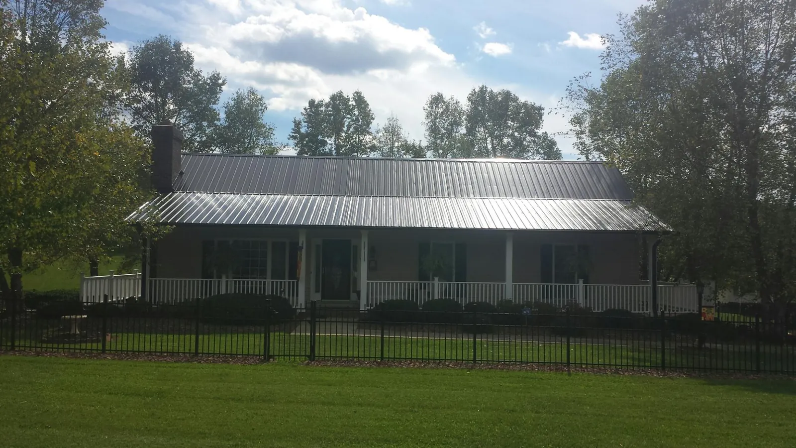 Gray metal roof on a brick ranch with a full width front porch — Gutter Guard Installation work by our crew in Hood