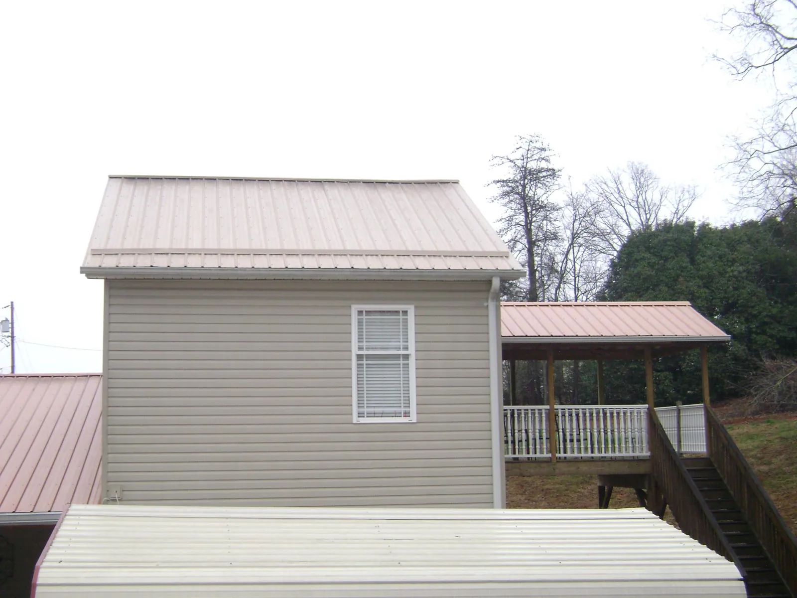 Tan metal roofs on a two story addition and attached porch, from a Roof Replacement job in Hood