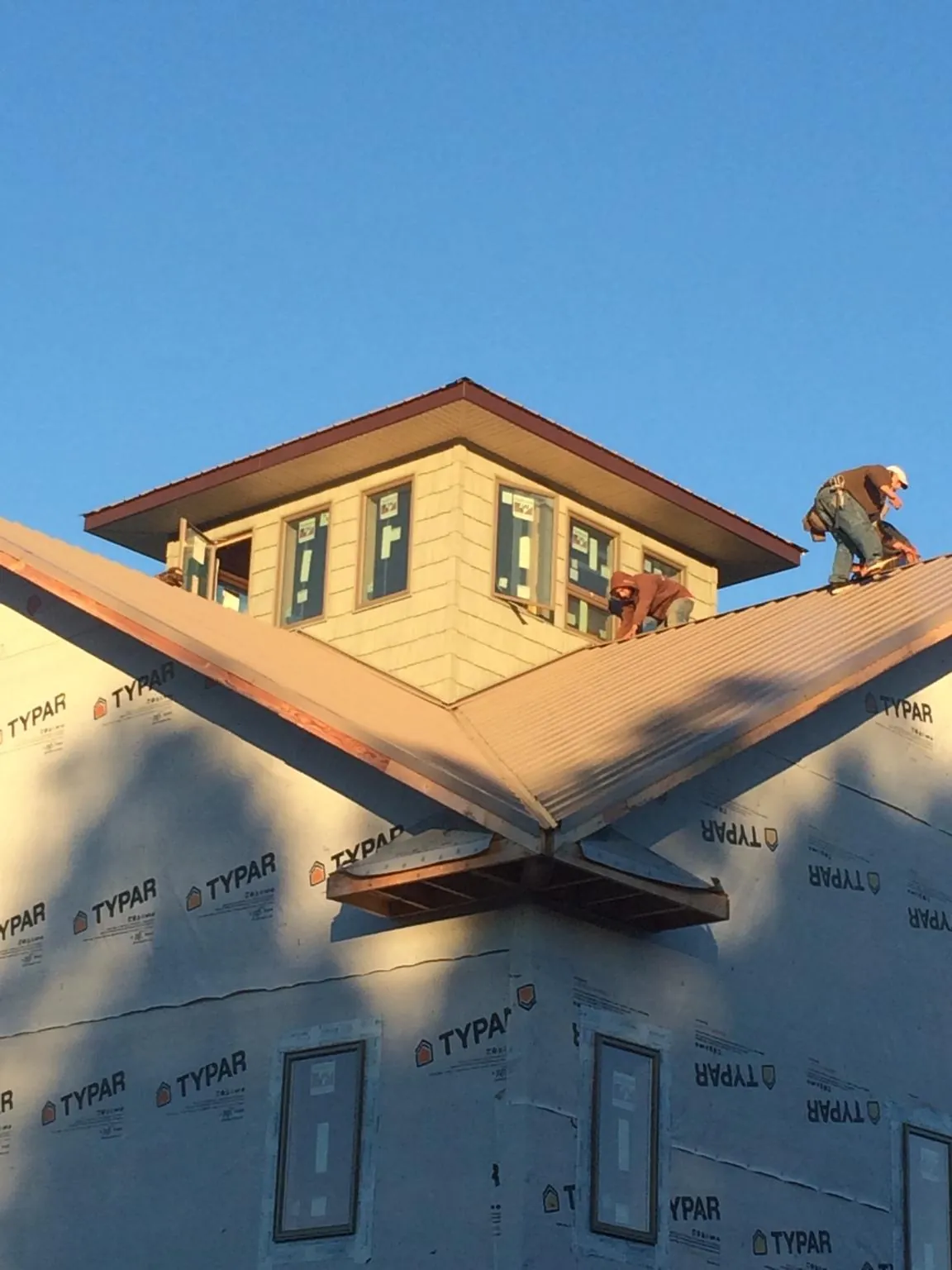 Roofers working around a rooftop cupola on a new metal roof at sunset — Roof Waterproofing in Hood by Roofing Brothers